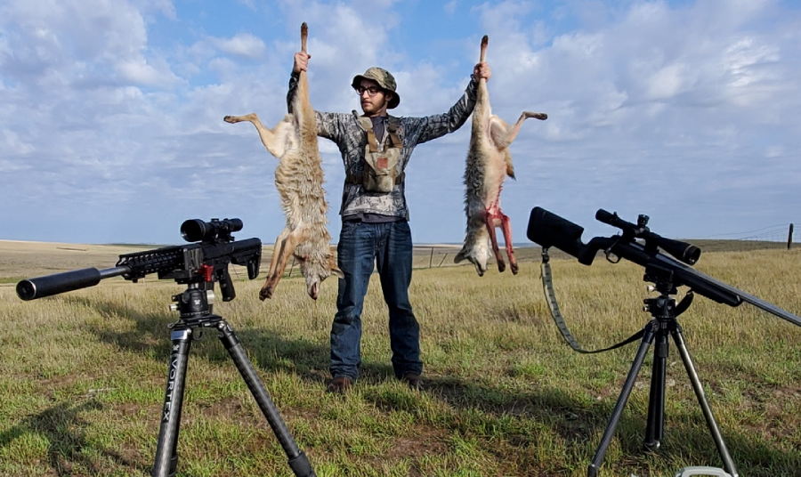 Hunter poses with two dead coyotes