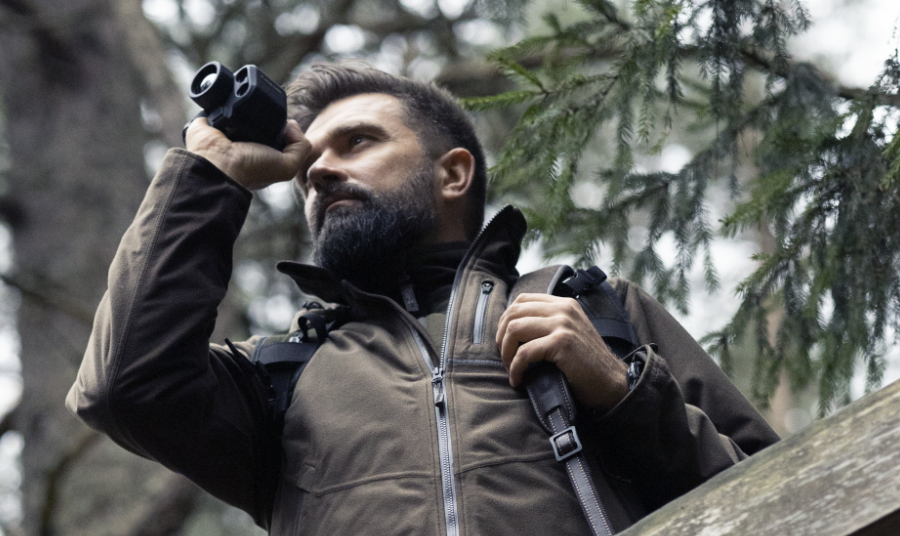 Hunter observing from the trees using a thermal monocular
